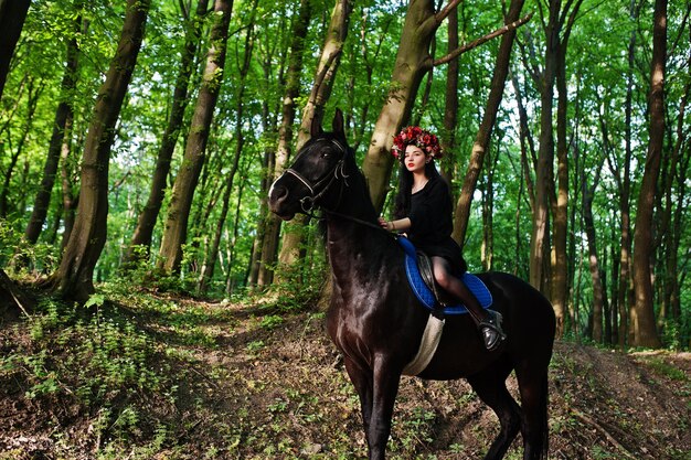 Chica mística en ropa de corona en negro a caballo en madera