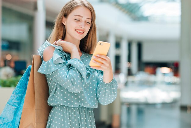 Chica de moda control de teléfono en el centro comercial