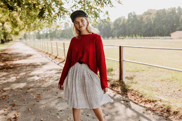 Chica de moda posando junto a las hojas de otoño.