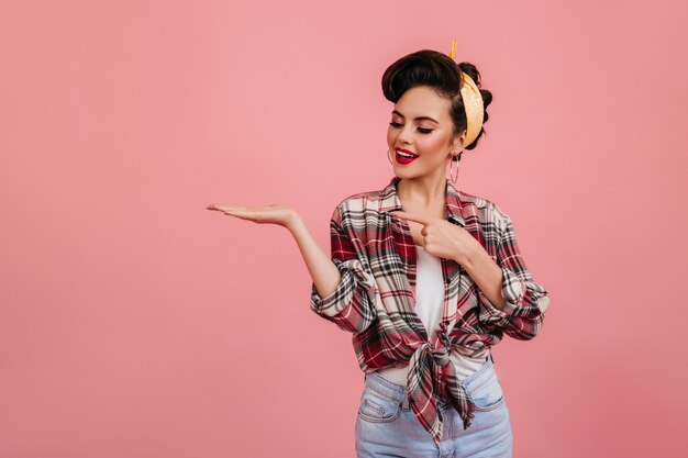 Chica modela agradable posando con la mano hacia arriba. Disparo de estudio de linda mujer joven en traje vintage.