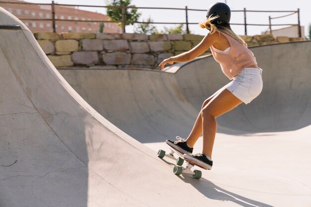 Chica moderna urbana skating en medio tubo