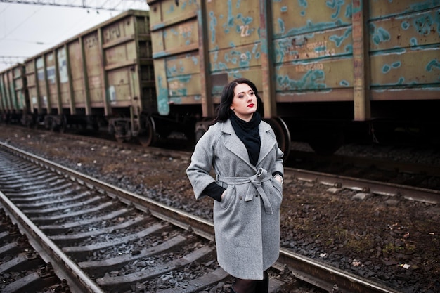 Chica morena con abrigo gris posó en la estación de tren