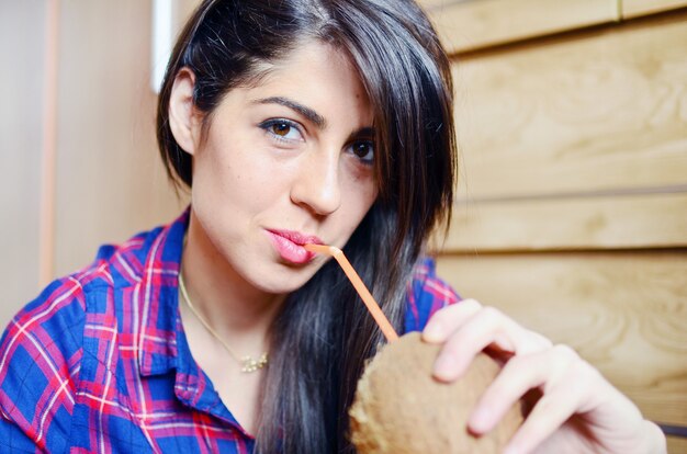 Chica morena bebiendo agua de coco