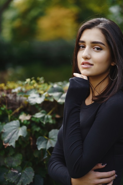 chica morena caminando por el parque durante el otoño