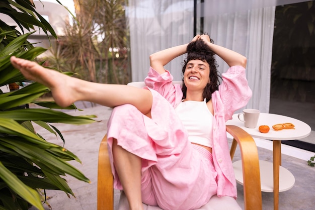 Foto gratuita chica morena caucásica joven relajada con los ojos cerrados toca el cabello sentado en una silla al aire libre gente emociones sinceras concepto de estilo de vida