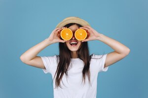 Foto gratuita chica morena con falda amarilla sostiene naranjas ante sus ojos y sonríe