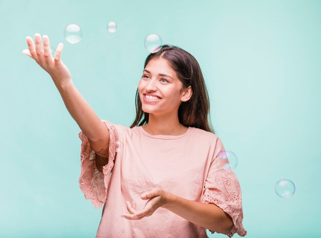 Chica morena jugando con burbujas de jabón