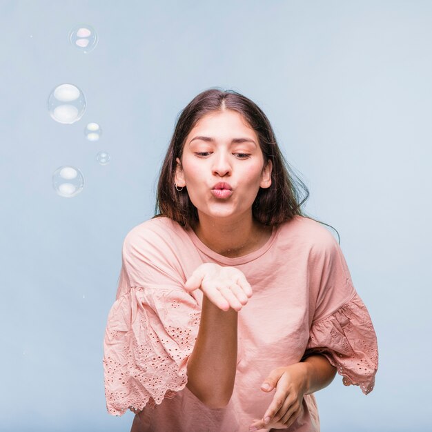 Chica morena jugando con burbujas de jabón