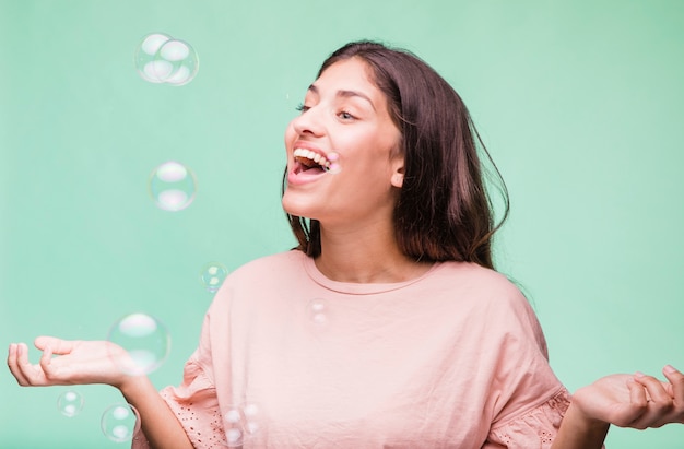 Chica morena jugando con burbujas de jabón