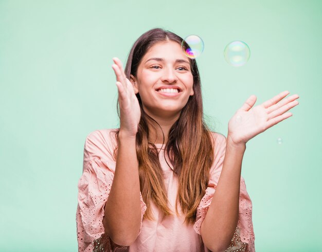 Chica morena jugando con burbujas de jabón