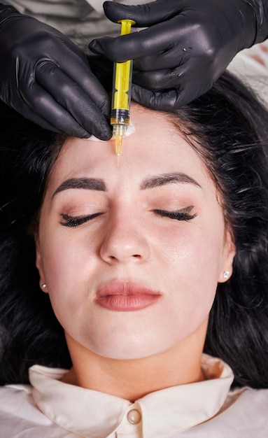 Foto gratuita chica morena en la oficina de cosmetología durante el procedimiento de plasmolifting acostada con los ojos cerrados