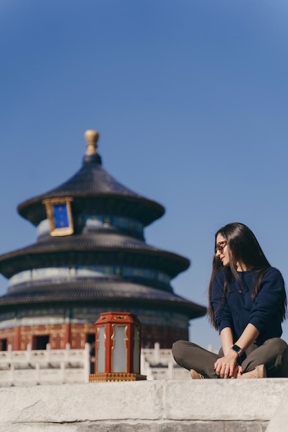 Chica morena sentada en los escalones por el templo de Heven en China