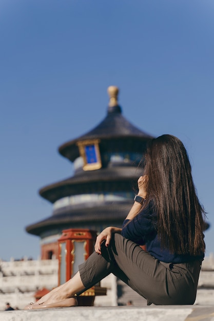 Chica morena sentada en los escalones por el templo de Heven en China