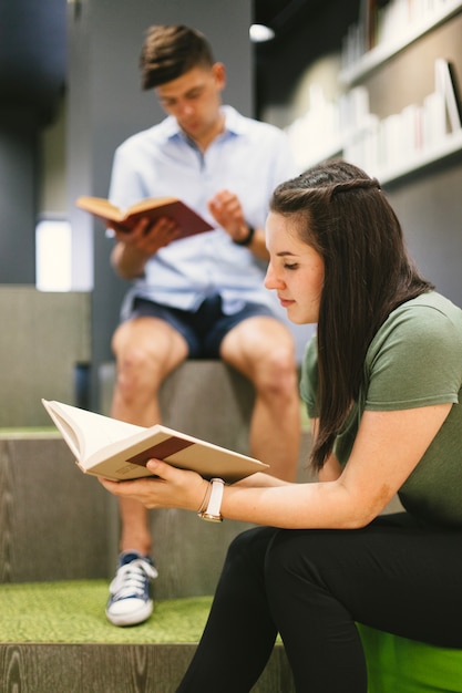 Foto gratuita chica morena sentada y leyendo el libro