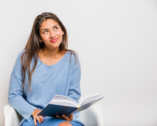 Foto gratuita chica morena sentada leyendo un libro