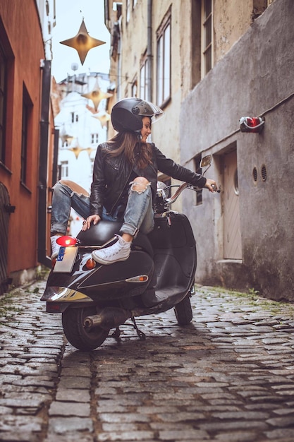 Chica morena sexy con gafas de sol sentada en Vespa scooter.