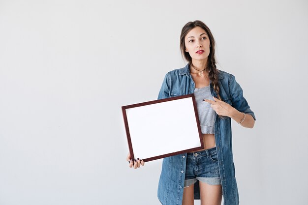 Chica mostrando a un cartel o cartel blanco en blanco vacío