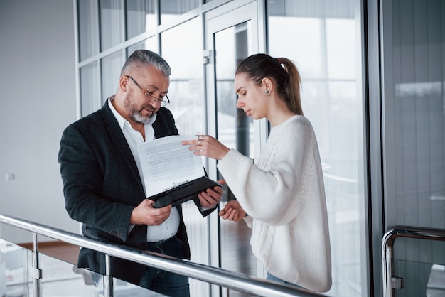 Chica mostrando los resultados del trabajo a su jefe en gafas y barba gris