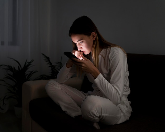 Chica con móvil por la noche en la cama