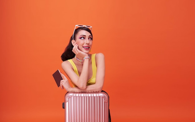 Chica mujer feliz con maleta y pasaporte mirando en el fondo del espacio de copia naranja