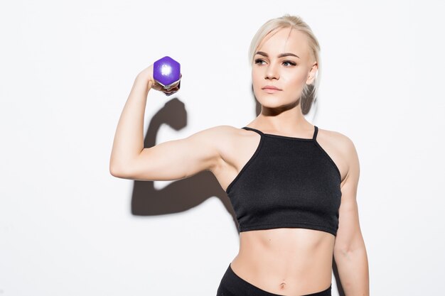 Chica musculosa fuerte preparándose para una competencia con pesas azules sobre blanco