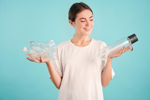 Chica muy sonriente eligiendo alegremente eco en lugar de botellas de plástico sobre fondo colorido aislado