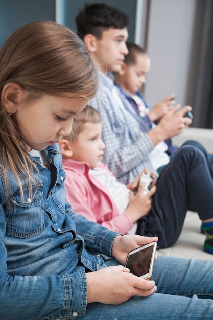 Chica navegando smartphone cerca de hermanos y hermana