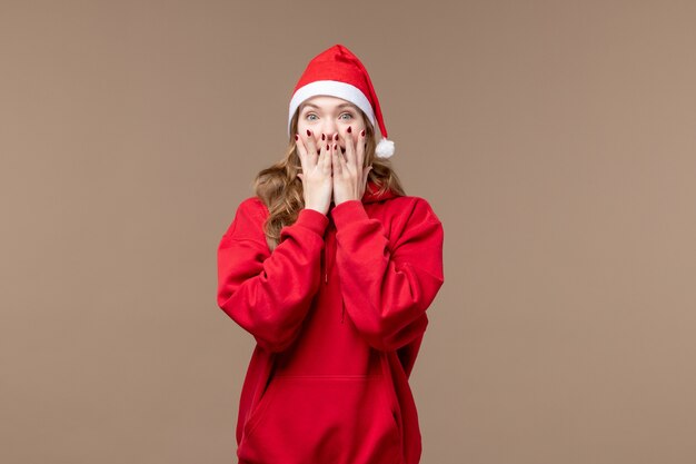 Chica de Navidad vista frontal con cara emocionada sobre un fondo marrón vacaciones año nuevo navidad