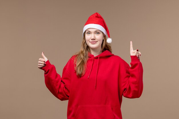 Chica de Navidad de vista frontal con expresión encantada sobre fondo marrón Navidad de vacaciones de mujer