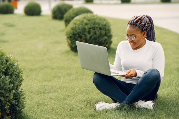 Chica negra en una ciudad de verano con una computadora portátil