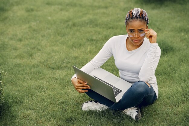 Chica negra en una ciudad de verano con laptop