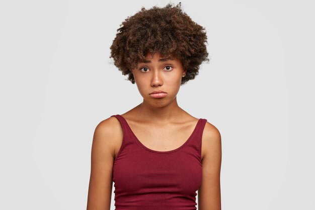 Chica negra ofensiva frunce los labios con expresión de descontento, siente frustración, está abatida por noticias negativas
