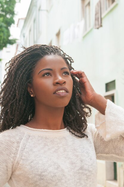 Chica negra pensativa caminando por el callejón de la ciudad