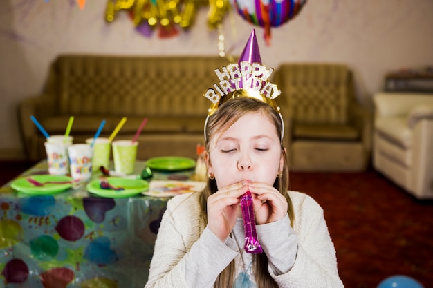 Chica con noisemaker en la fiesta de cumpleaños