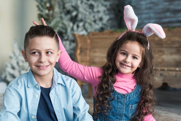 Chica en orejas de conejo haciendo cuernos con dedos para niño