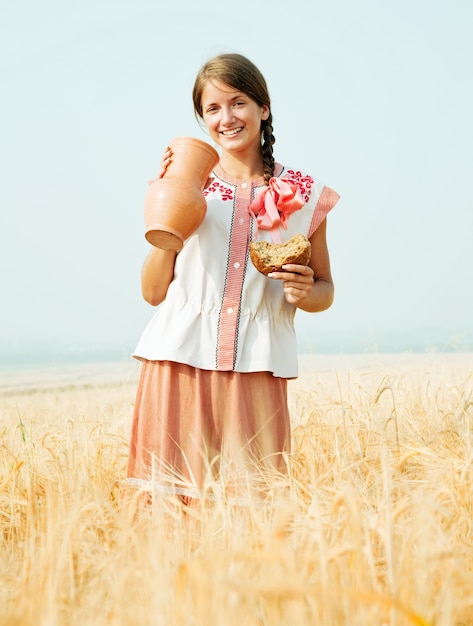 Foto gratuita chica con pan y jarra en el campo