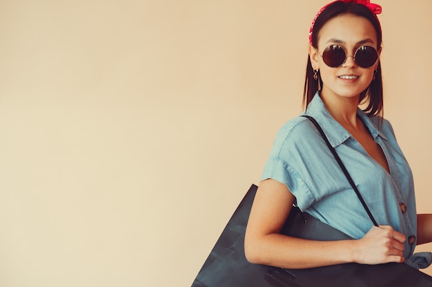 Chica en una pared amarilla con bolsas de compras