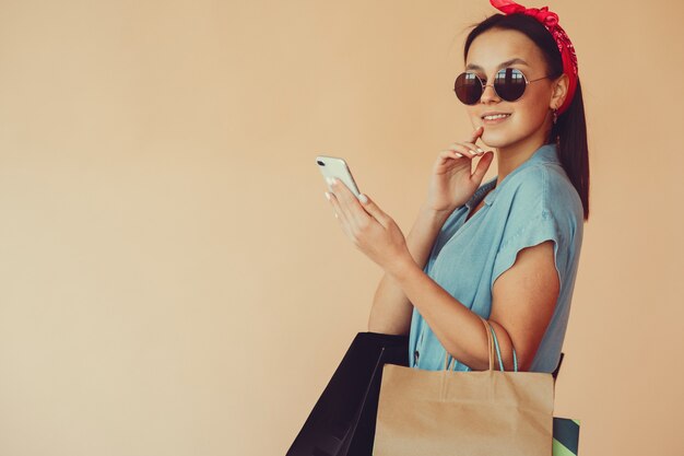 Chica en una pared amarilla con bolsas de compras