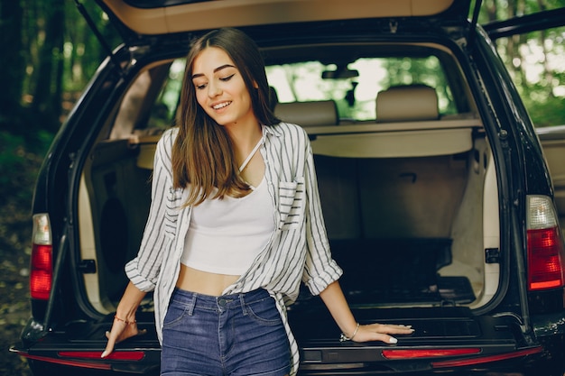 Chica en un parque de verano cerca del coche