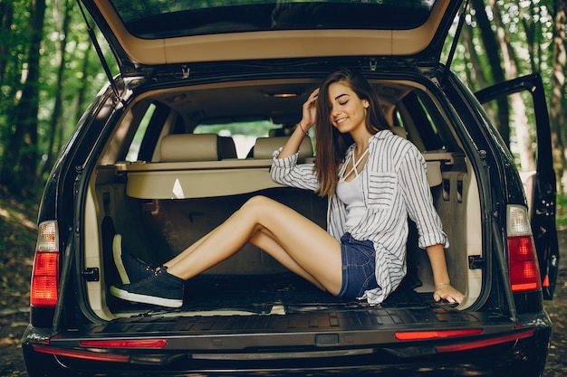 Chica en un parque de verano cerca del coche