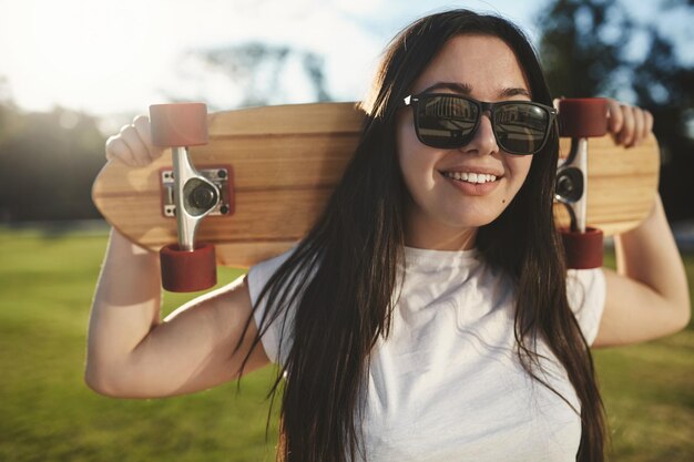 Chica patinadora relajada despreocupada de primer plano relajándose en la hierba en el soleado