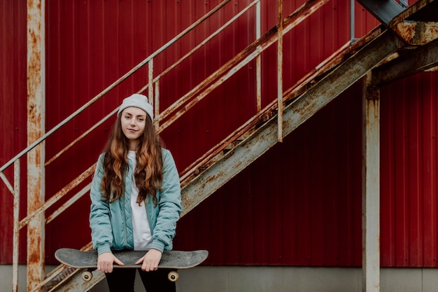 Chica patinadora sosteniendo su patineta delante de ella