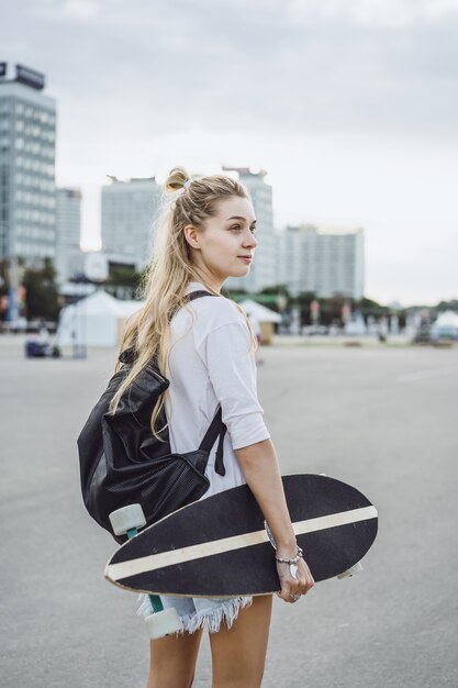 Chica con patines de pelo largo en una patineta. calle, deportes activos