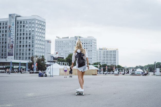 Chica con patines de pelo largo en una patineta. calle, deportes activos