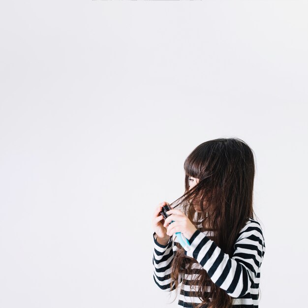 Chica peinando el cabello enredado