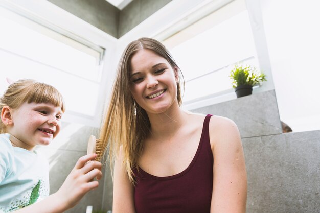 Chica peinando cabello de mujer sonriente