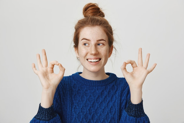 Foto gratuita chica pelirroja alegre sonriendo, mostrando bien en aprobación, asegura que todo está bien