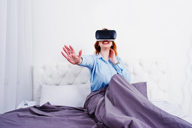 Chica pelirroja en la cama con gafas vr en la sala de estudio