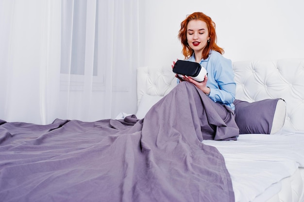 Chica pelirroja en la cama con gafas vr en la sala de estudio