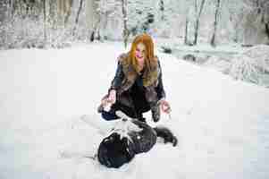 Foto gratuita chica pelirroja caminando en el parque con perro husky en día de invierno